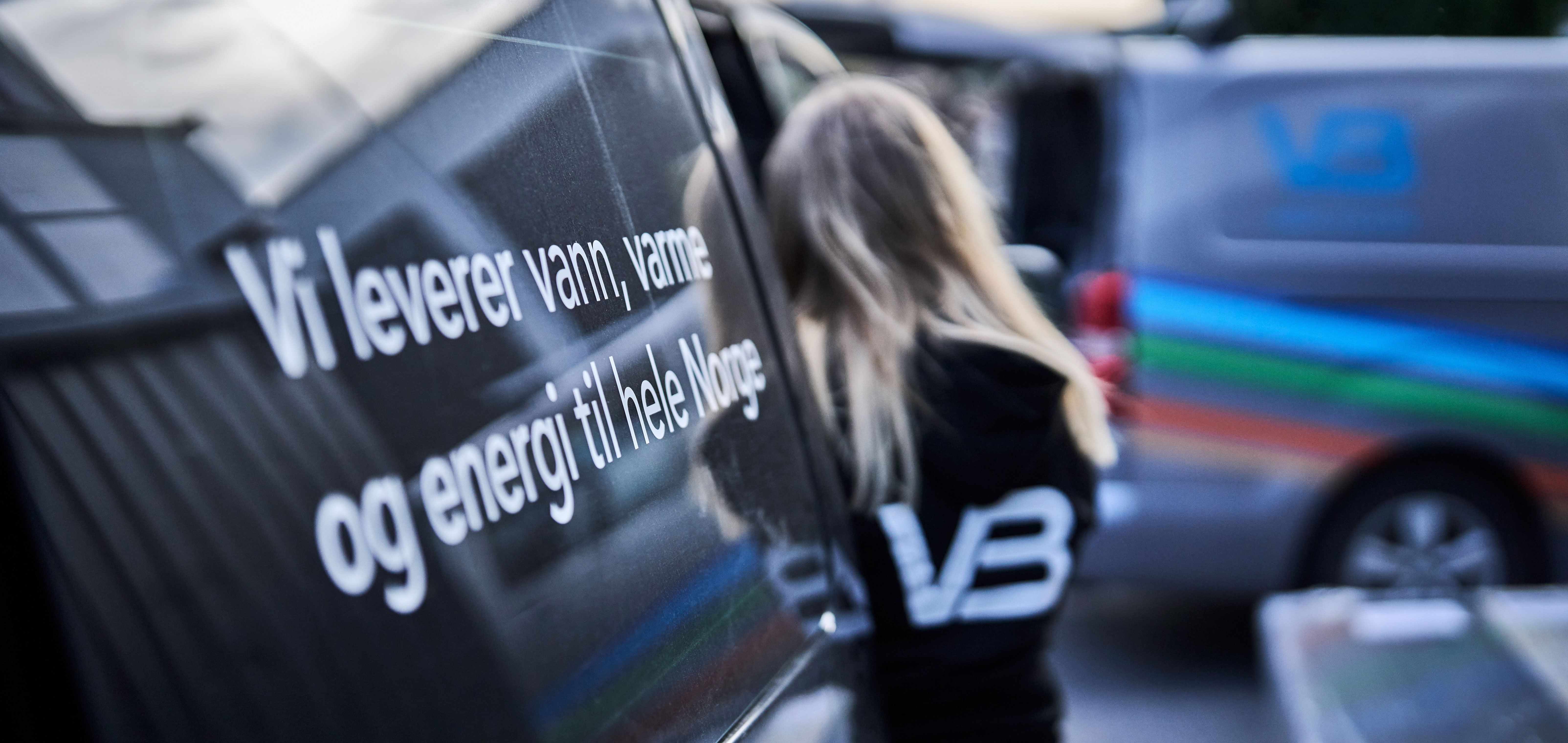 Rørlegger foran firmabil med teksten Vi leverer vann, varme og energi til hele Norge